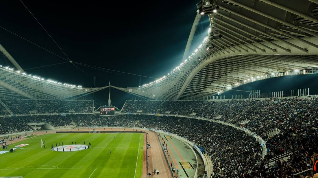 Stadion sepak bola penuh penonton di bawah lampu malam